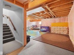 Staircase with carpeted treads and wood handrail descending to a concrete floor - 