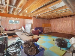 Unfinished basement space featuring exposed wood joists and subflooring, insulated walls, and visible ductwork - 