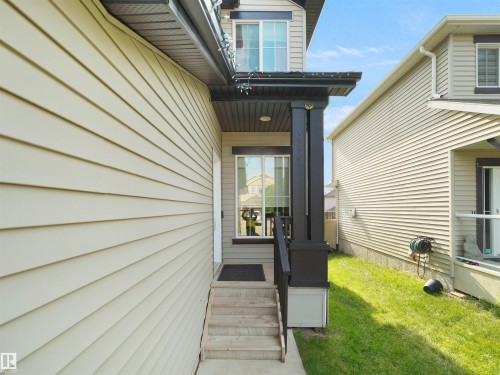 Front entrance featuring a covered porch with dark-toned pillars, concrete steps, and a dark welcome mat - 1716 60 Street Sw, Edmonton, AB - Outdoor