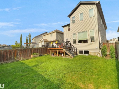 Spacious backyard featuring a manicured lawn, a wooden fence, and a multi-level deck with black railings - 1716 60 Street Sw, Edmonton, AB - Outdoor