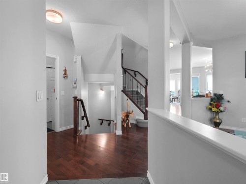 Foyer featuring wood-finish flooring, a contemporary staircase with dark wood handrails and wrought iron spindles, and a light gray wall palette - 1716 60 Street Sw, Edmonton, AB - Indoor Photo Showing Other Room