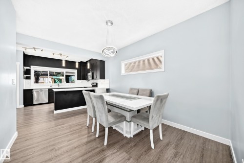 Contemporary dining area featuring wood-finish flooring and a modern pendant light fixture - 17508 58 Street Nw, Edmonton, AB - Indoor Photo Showing Dining Room