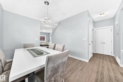 Dining area featuring a contemporary chandelier, light wood-finish flooring, white baseboards, and a white interior door - 