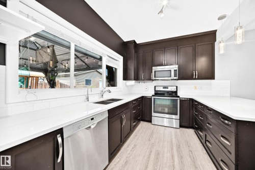U-shaped kitchen featuring dark wood cabinetry and light countertops - 17508 58 Street Nw, Edmonton, AB - Indoor Photo Showing Kitchen With Double Sink