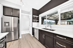 Modern kitchen featuring wood-finish flooring, dark cabinetry, and light countertops - 