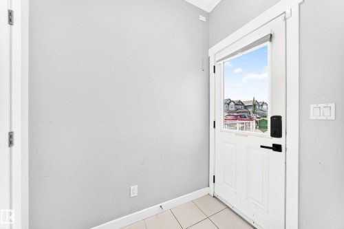 Entryway featuring a white paneled door with a rectangular window, matte black hardware, and light-toned tile flooring - 17508 58 Street Nw, Edmonton, AB - Indoor Photo Showing Other Room