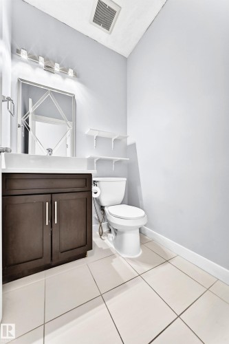 Powder room featuring a dark wood-finish vanity with dual doors, a rectangular sink, and a modern light fixture - 17508 58 Street Nw, Edmonton, AB - Indoor Photo Showing Bathroom
