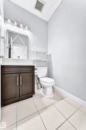 Powder room featuring a dark wood-finish vanity with dual doors, a rectangular sink, and a modern light fixture - 