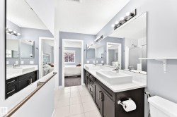 Bathroom featuring dual vessel sinks, dark wood-finish vanity cabinetry, and extensive mirror space - 