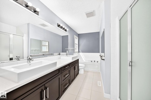 Double vanity with rectangular vessel sinks, dark wood-finish cabinetry, and a full-width mirror - 17508 58 Street Nw, Edmonton, AB - Indoor Photo Showing Bathroom