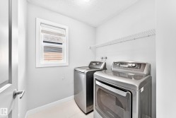 Dedicated laundry room featuring light-toned walls, a white wire shelf, a window with blinds, and light-colored flooring - 
