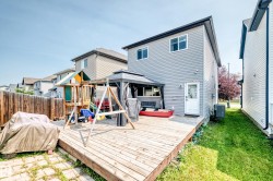 Spacious backyard featuring a wood deck, partial privacy fencing, and a gray-sided exterior with white trim - 