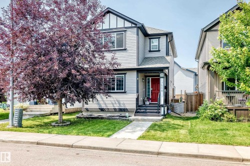 Two-story residence featuring light gray siding with dark trim accents and a vibrant red entry door - 17508 58 Street Nw, Edmonton, AB - Outdoor With Facade