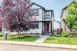 Two-story residence featuring light gray siding with dark trim accents and a vibrant red entry door - 