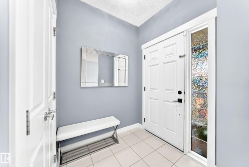 Entryway featuring a paneled door with matte black hardware, an etched glass sidelight, and light tile flooring - 17508 58 Street Nw, Edmonton, AB - Indoor Photo Showing Other Room