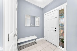Entryway featuring a paneled door with matte black hardware, an etched glass sidelight, and light tile flooring - 