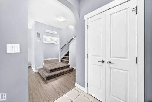 Entryway featuring wood-finish flooring, light gray wall paint, and white paneled doors with polished chrome hardware - 17508 58 Street Nw, Edmonton, AB - Indoor Photo Showing Other Room