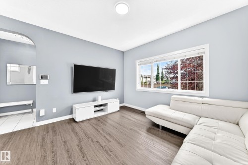 Spacious room featuring wood-finish flooring, light blue wall paint, and a large window with white trim - 17508 58 Street Nw, Edmonton, AB - Indoor Photo Showing Living Room