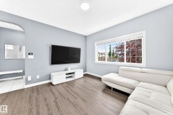 Spacious room featuring wood-finish flooring, light blue wall paint, and a large window with white trim - 