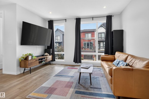Spacious living area featuring light wood-finish flooring and ample natural light through large windows - #84 1304 Rutherford Rd Sw, Edmonton, AB - Indoor Photo Showing Living Room