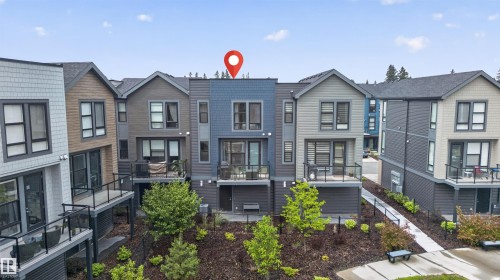 Contemporary townhome featuring multi-level exterior siding, private balconies with glass railings, and a landscaped terraced yard with a concrete pathway - #84 1304 Rutherford Rd Sw, Edmonton, AB - Outdoor With Facade