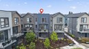 Contemporary townhome featuring multi-level exterior siding, private balconies with glass railings, and a landscaped terraced yard with a concrete pathway - #84 1304 Rutherford Rd Sw, Edmonton, AB  - Outdoor With Facade 