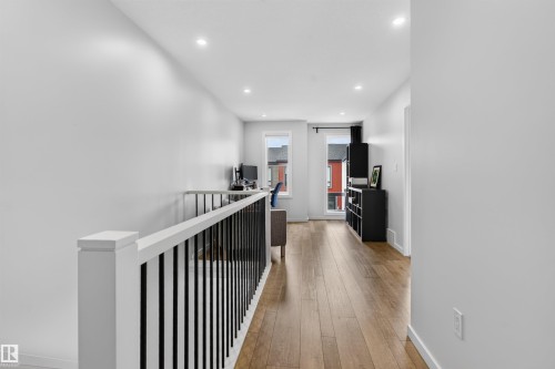 Upper-level hallway featuring wood-finish flooring, recessed lighting, white walls, and a contemporary stair railing with black balusters - #84 1304 Rutherford Rd Sw, Edmonton, AB - Indoor Photo Showing Other Room