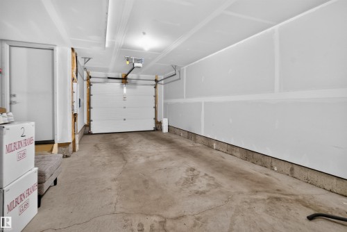 Attached garage featuring a concrete floor, automated overhead door, and a dedicated personnel door - #84 1304 Rutherford Rd Sw, Edmonton, AB - Indoor Photo Showing Garage