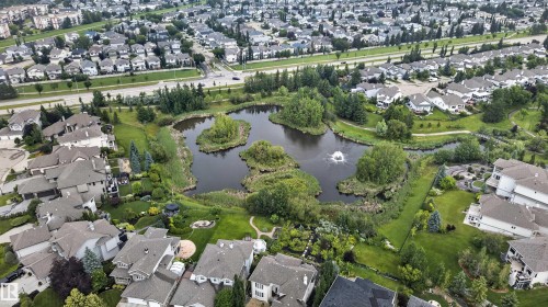 Aerial perspective showcasing a residential community centered around a naturalized pond with multiple islands - #84 1304 Rutherford Rd Sw, Edmonton, AB - Outdoor With View