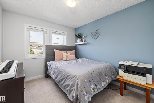 Carpeted room featuring dual windows, a paneled headboard, and a contrasting accent wall - 12305 173A Avenue Nw, Edmonton, AB - Indoor Photo Showing Bedroom
