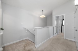 Carpeted landing featuring a contemporary flush-mount ceiling light, white painted walls, white trim, and a staircase with a white handrail - 
