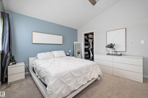 Spacious room featuring vaulted ceilings, plush carpeting, a built-in closet with shelving, and large window with dark-toned curtain rods - 12305 173A Avenue Nw, Edmonton, AB - Indoor Photo Showing Bedroom