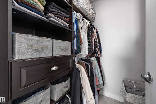 Built-in closet system featuring dark wood-finish cabinetry, integrated shelving, and a drawer with brushed nickel hardware - 12305 173A Avenue Nw, Edmonton, AB - Indoor With Storage
