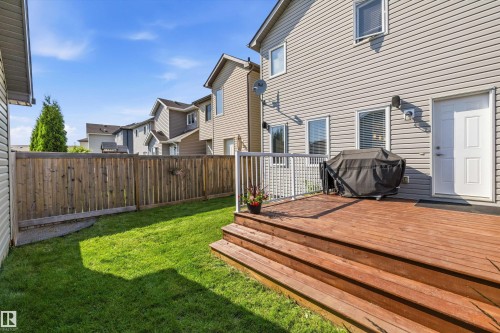 Rear exterior featuring a spacious wood deck with white railings and stairs, a fully fenced yard with a wood privacy fence, and a grassy area - 12305 173A Avenue Nw, Edmonton, AB - Outdoor With Exterior