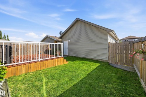 Expansive backyard featuring a wood deck with white railing, a manicured lawn, wooden privacy fencing, and neutral-toned siding on the dwelling - 12305 173A Avenue Nw, Edmonton, AB - Outdoor