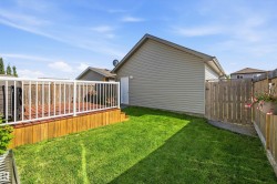 Expansive backyard featuring a wood deck with white railing, a manicured lawn, wooden privacy fencing, and neutral-toned siding on the dwelling - 
