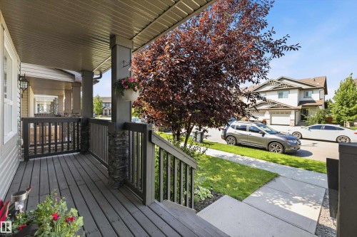 Covered front porch with wood-finish decking and dark railing - 12305 173A Avenue Nw, Edmonton, AB - Outdoor With Deck Patio Veranda