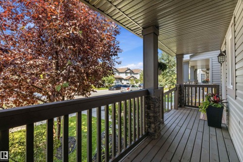 Covered front porch featuring wood-finish decking, stone-clad pillars, and exterior siding - 12305 173A Avenue Nw, Edmonton, AB - Outdoor With Exterior