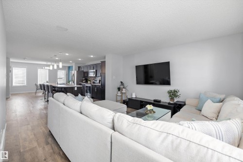 Expansive open-concept living area featuring light wood-finish flooring, recessed lighting, and a modern kitchen with dark cabinetry - 12305 173A Avenue Nw, Edmonton, AB - Indoor Photo Showing Living Room