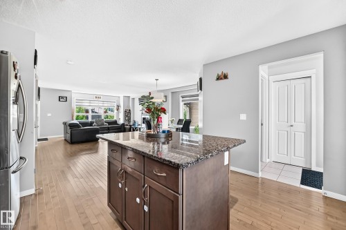 Kitchen island featuring a granite countertop, rich wood-finish cabinetry, and brushed nickel hardware - 5280 21 Avenue Sw, Edmonton, AB - Indoor Photo Showing Kitchen