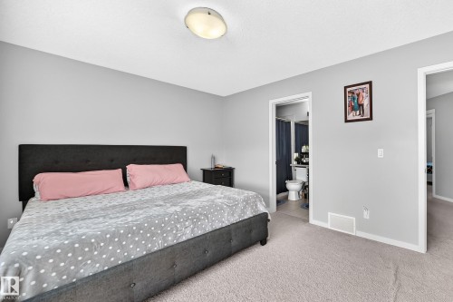 Spacious bedroom featuring light grey walls, light-colored carpeting, a flush-mount ceiling light fixture, and white trim - 5280 21 Avenue Sw, Edmonton, AB - Indoor Photo Showing Bedroom