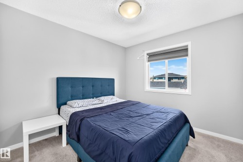 Bright room featuring neutral wall paint, a single window with a window blind, light-colored carpet flooring, and a flush-mount ceiling light fixture - 5280 21 Avenue Sw, Edmonton, AB - Indoor Photo Showing Bedroom