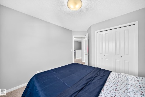 Carpeted room featuring a ceiling-mounted light fixture, light gray walls, a white bi-fold closet, and white baseboards - 5280 21 Avenue Sw, Edmonton, AB - Indoor Photo Showing Bedroom