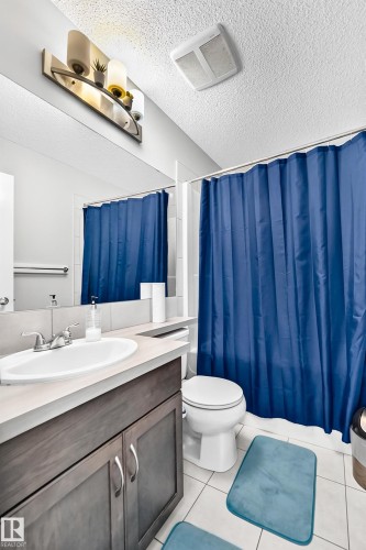 Bathroom featuring a single vanity with a white oval sink, chrome faucet, and a dark wood-finish cabinet - 5280 21 Avenue Sw, Edmonton, AB - Indoor Photo Showing Bathroom