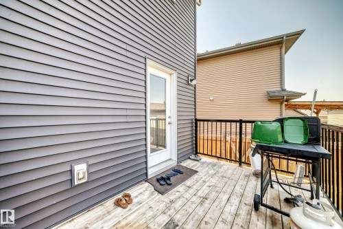 Private outdoor deck with wood-finish flooring, featuring a glass-paneled door, black metal railing, and durable gray siding - 5280 21 Avenue Sw, Edmonton, AB - Outdoor With Deck Patio Veranda With Exterior