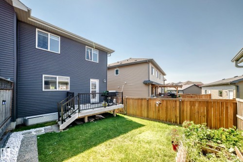 Rear exterior featuring dark horizontal siding, a wooden deck with black railings, and a manicured lawn - 5280 21 Avenue Sw, Edmonton, AB - Outdoor With Deck Patio Veranda With Exterior