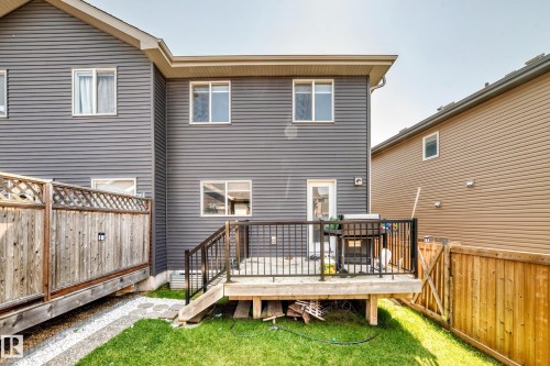 Rear exterior featuring grey siding, a wooden deck with black railings, and a fenced yard with a small grassy area - 5280 21 Avenue Sw, Edmonton, AB - Outdoor With Deck Patio Veranda With Exterior