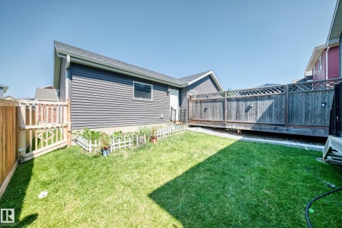 Expansive grass lawn with a perimeter wood fence featuring a gate - 5280 21 Avenue Sw, Edmonton, AB - Outdoor With Deck Patio Veranda