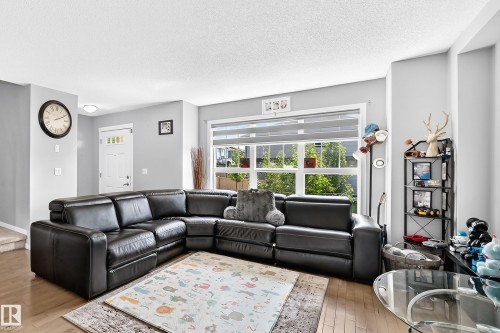 Bright living area featuring wood-finish flooring, light gray walls, and a large window with white trim - 5280 21 Avenue Sw, Edmonton, AB - Indoor Photo Showing Living Room