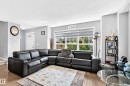 Bright living area featuring wood-finish flooring, light gray walls, and a large window with white trim - 5280 21 Avenue Sw, Edmonton, AB  - Indoor Photo Showing Living Room 